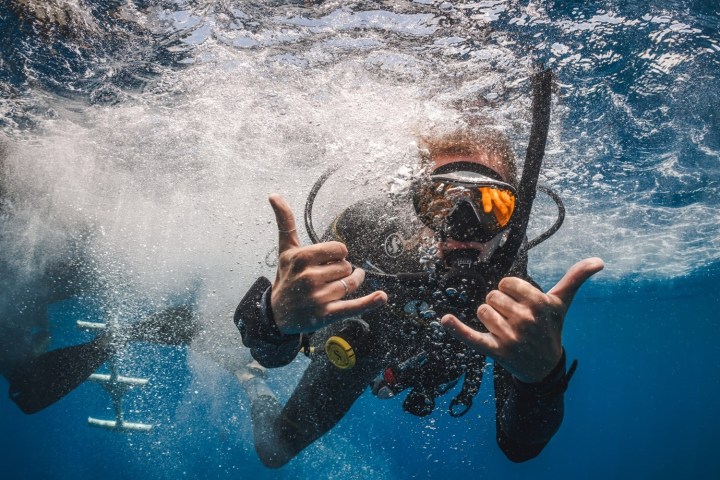 Scuba diver underwater making hand signs and bubbles.