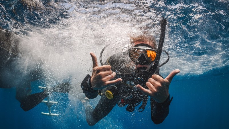 Scuba diver underwater making hand signs and bubbles.
