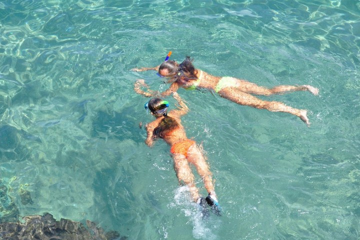 Two people snorkeling in clear blue water, wearing masks and snorkels.