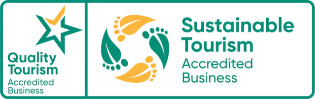Quality Tourism and Sustainable Tourism Accredited Business logos with a green and yellow leaf design.
